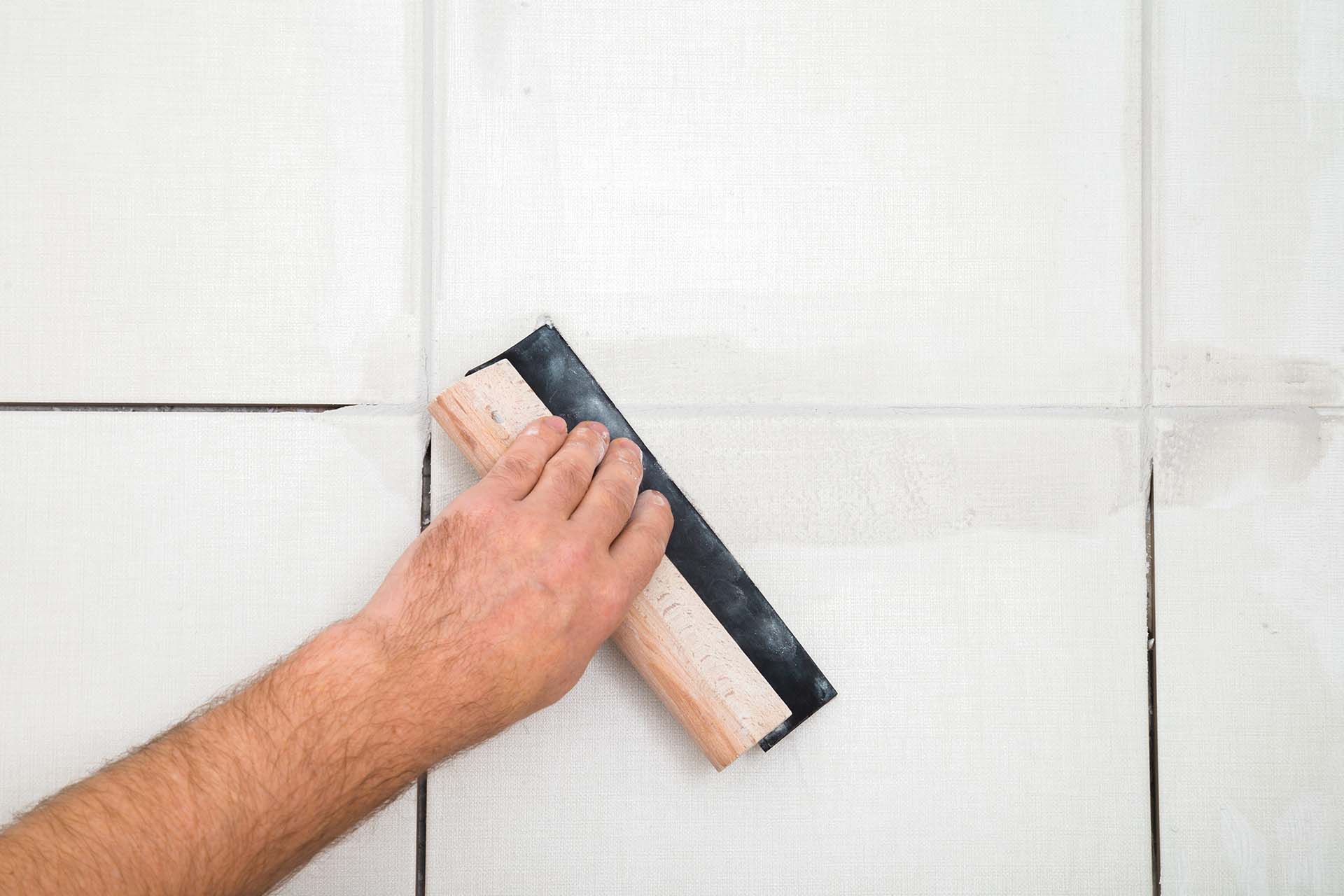 Craftsman carefully regrouting tile