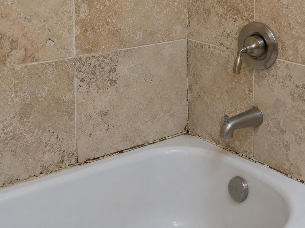 Cracked, mildewed shower caulk before recaulking in an Orlando, FL bathroom